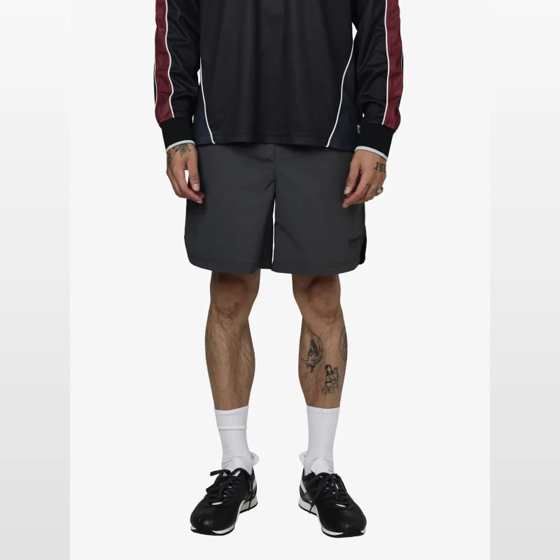 Man wearing dark grey woven running shorts with an elasticated waistband and curved side-hem vents.