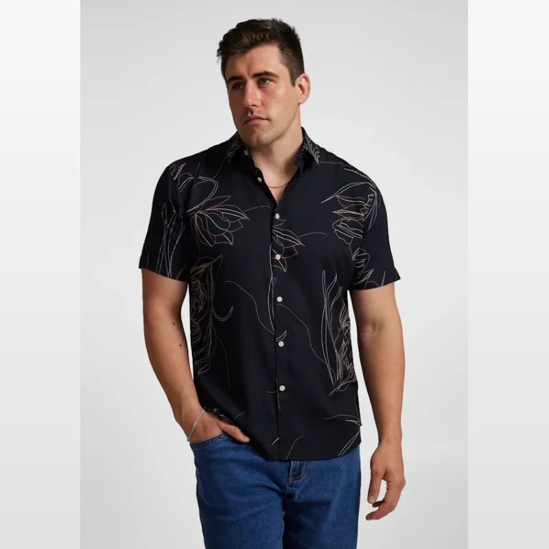 Man wearing a dark navy short sleeve shirt with a white floral outline print and white buttons.