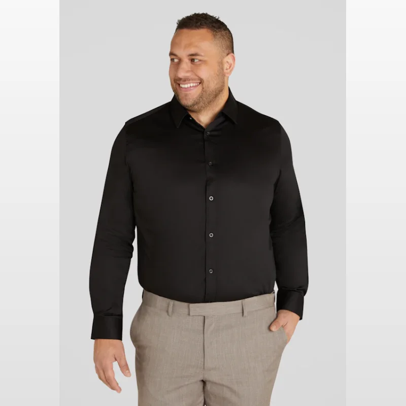 Man wearing a black long-sleeved dress shirt with a built-in collar and button-through front, paired with light brown trousers.