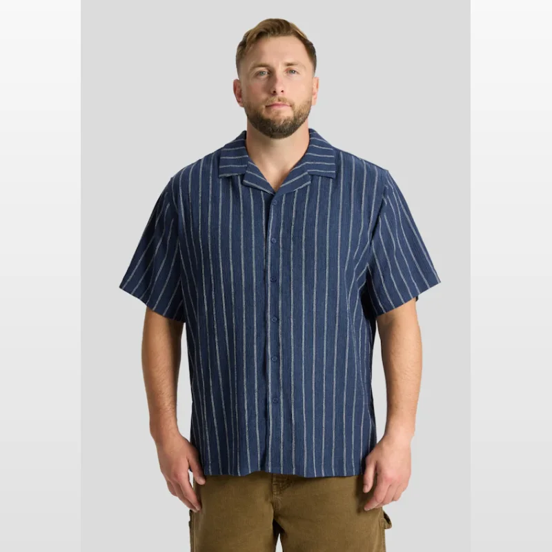 Man wearing a navy blue short sleeve shirt with thin white vertical stripes and a cuban collar.