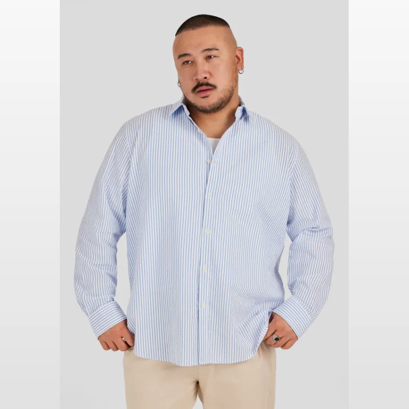 Man wearing a blue and white striped seersucker long sleeve shirt with a relaxed fit.