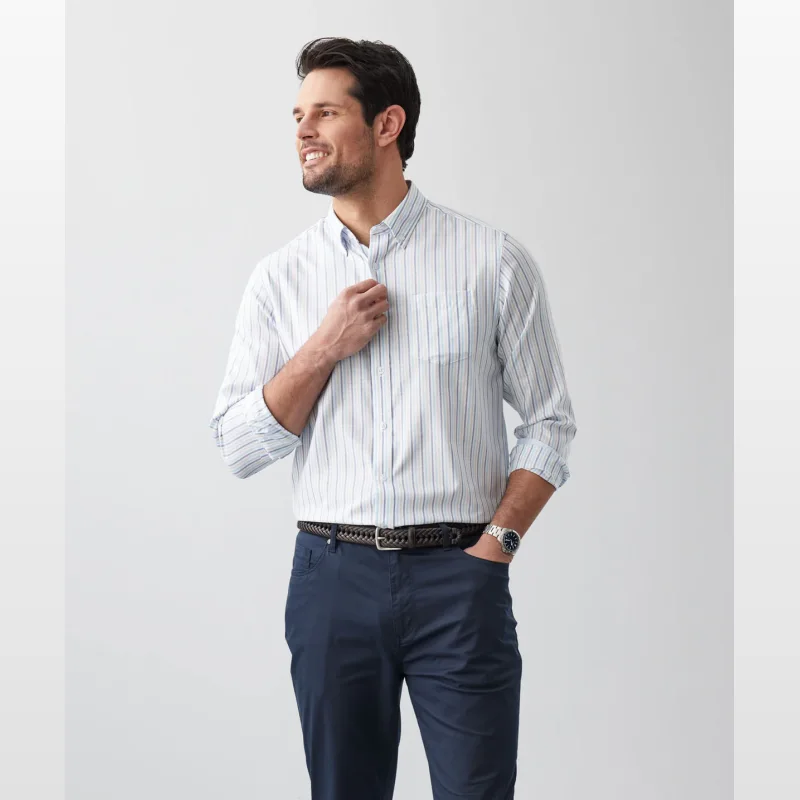 Man wearing a white long sleeve shirt with blue and light brown vertical stripes, buttoned down collar, and navy trousers.