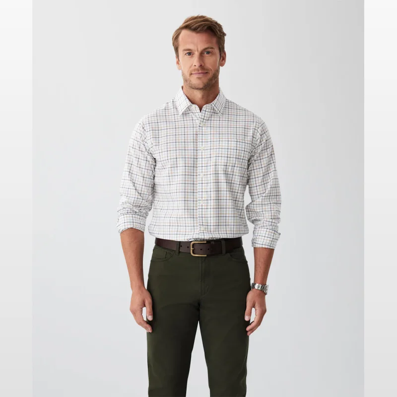 Man wearing a white long-sleeved shirt with a blue, green, and orange check pattern, paired with dark green trousers and a brown belt.