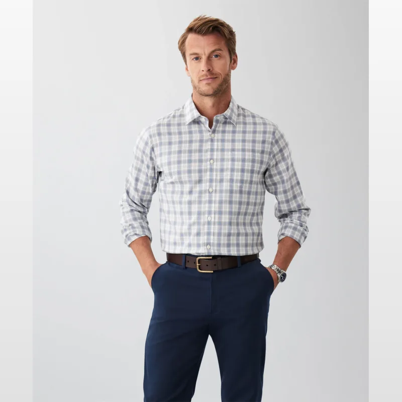 Man wearing a light blue and white checked long sleeve shirt with navy trousers and a brown belt.