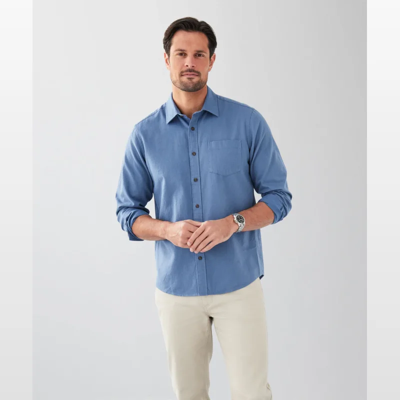 Man wearing a blue long sleeve Gazman casual shirt with a chest pocket and beige chinos.