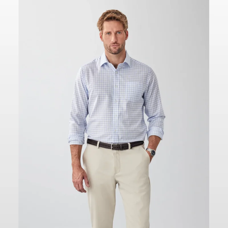 Man wearing a light blue long sleeve dobby check shirt with a chest pocket, paired with beige trousers and a dark brown belt.