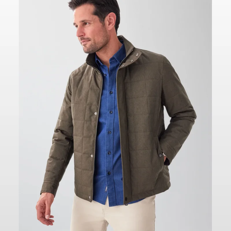Man wearing a dark olive green, quilted, showerproof Gazman Pathfinder jacket with a stand collar and concealed front closure, over a blue button-up shirt.