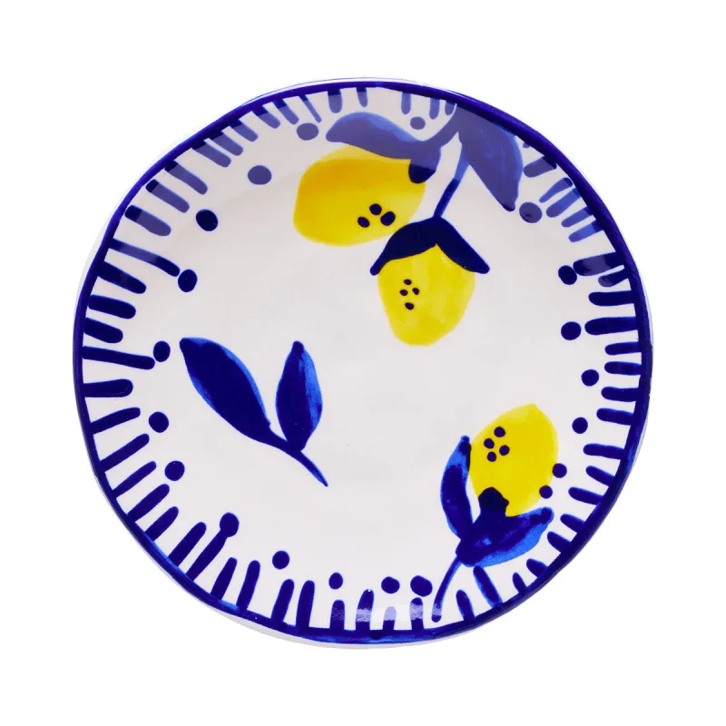 A white ceramic cake plate with a hand-painted design of yellow lemons and blue leaves, bordered by blue dashes and dots.