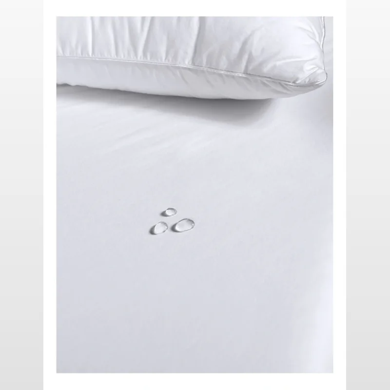 White bamboo cotton jersey waterproof mattress protector with water droplets on the surface and a white pillow in the background.