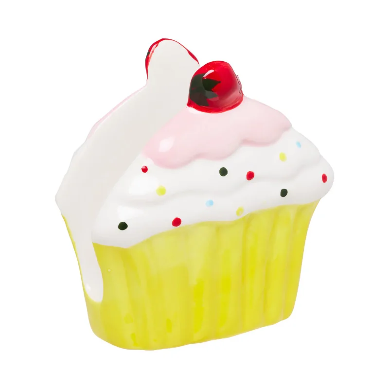 A ceramic napkin holder shaped like a cupcake with yellow frosting, white icing, pink frosting swirl, and a red cherry on top.