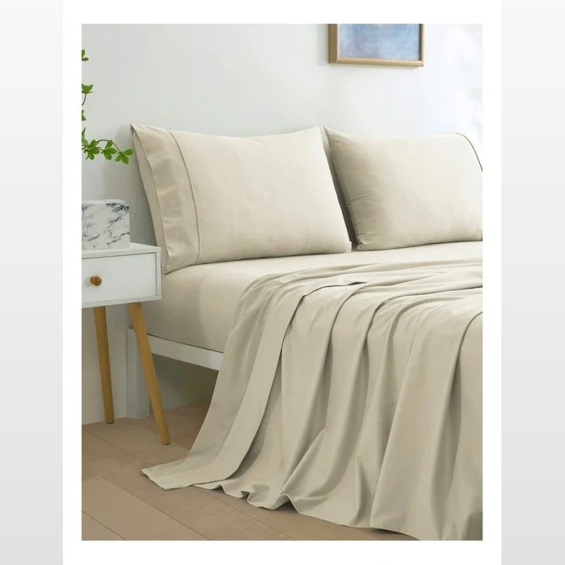 A close-up view of a cream-coloured micro flannel sheet set, including a flat sheet and pillowcases, on a bed.