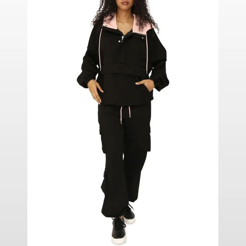 Woman wearing black cargo trackpants with a black hooded jacket with pink trim