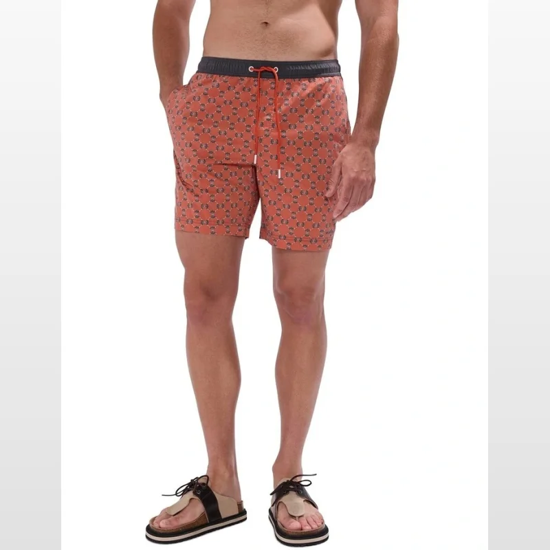 Man wearing Manta-Slay Swim Shorts in Rust Multi, featuring a bold graphic print, drawstring waistband, and side pockets.
