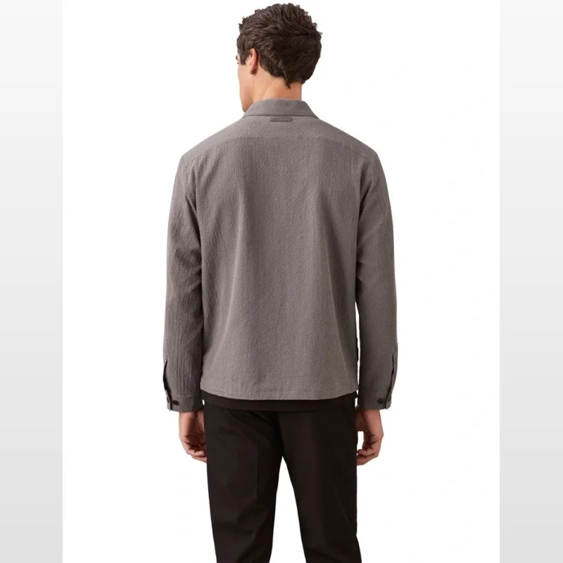 Man wearing a pewter-coloured seersucker long sleeve shirt jacket with a collared neckline and full zip closure, viewed from the back.