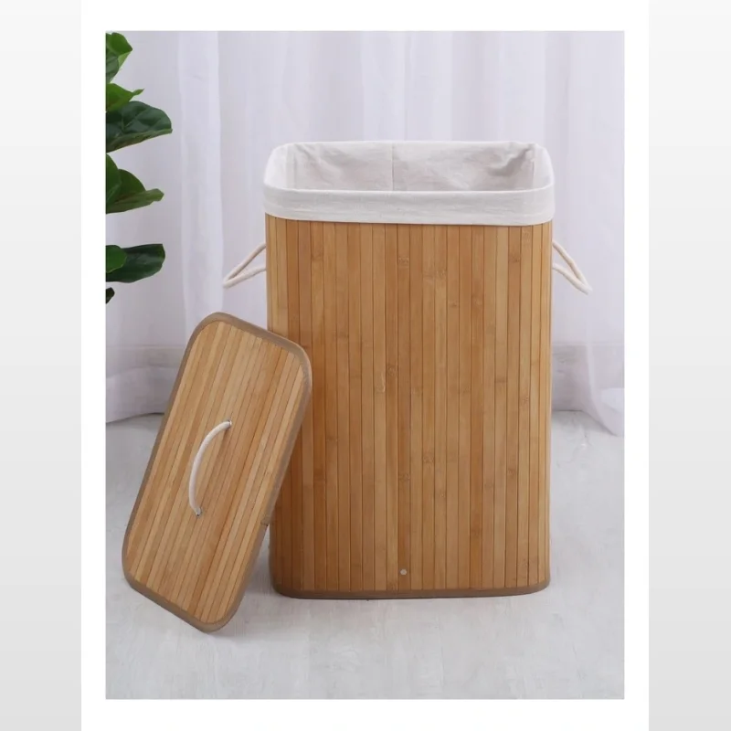 A rectangular bamboo laundry hamper with a removable lid, featuring a white polycotton liner and rope handles. The lid is placed next to the hamper.