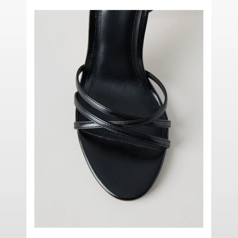 Close-up of a black Cassandra stiletto sandal with multiple thin straps across the toe and a round toe shape.