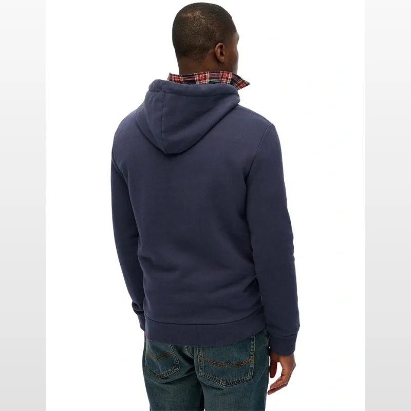 Man wearing a navy blue Superdry relaxed fit hoodie with a drawcord hood and ribbed cuffs and hem. The collar of a red and black plaid shirt is visible underneath.