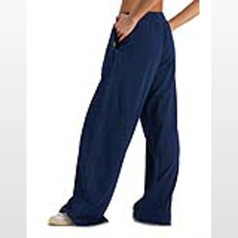 A person wearing navy blue wide leg track pants with cuffed ankles and side pockets.
