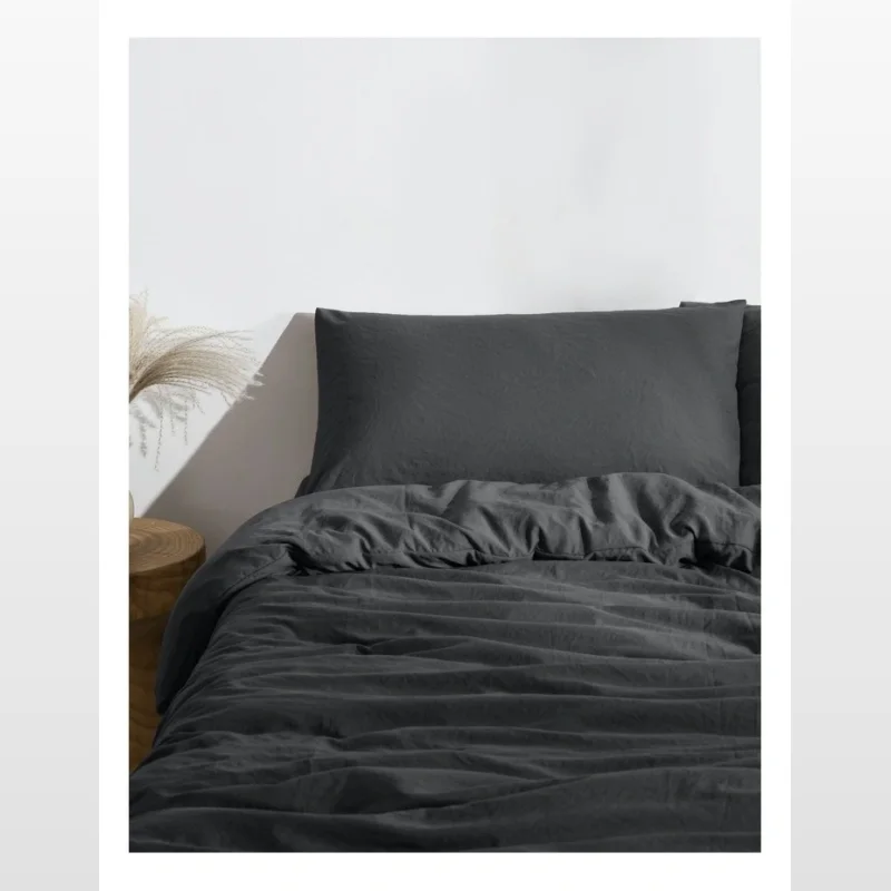 A close-up view of a black superfine washed microfibre quilt cover set on a bed, showing the texture of the fabric.