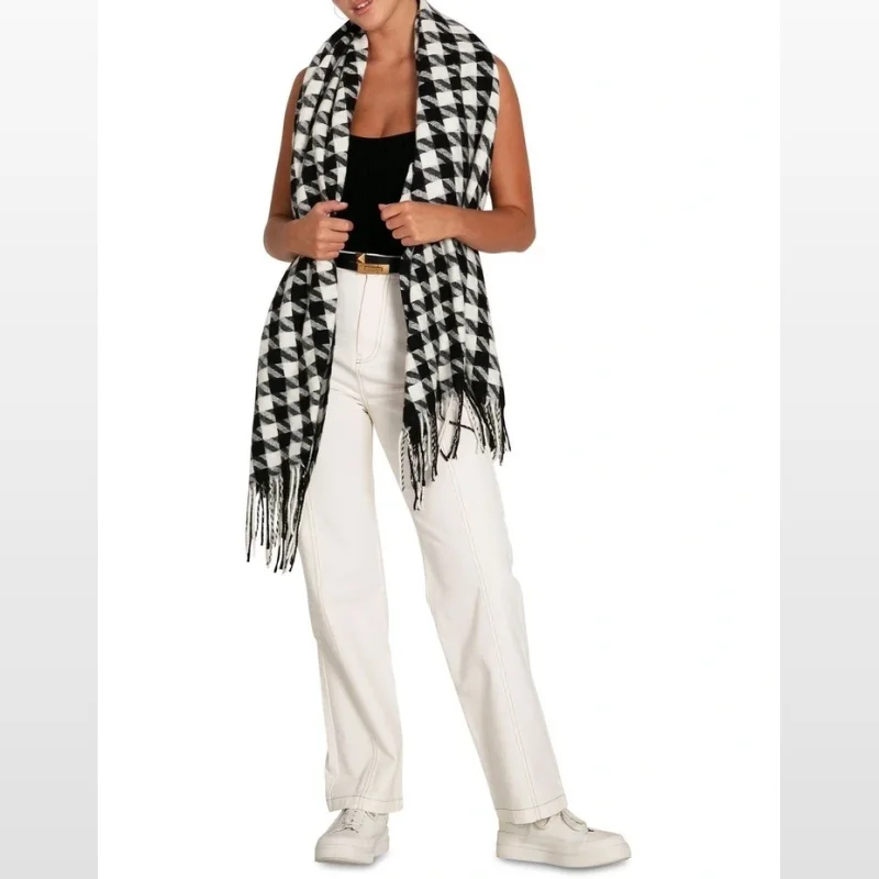 Woman wearing a black and white houndstooth scarf with fringe detail.