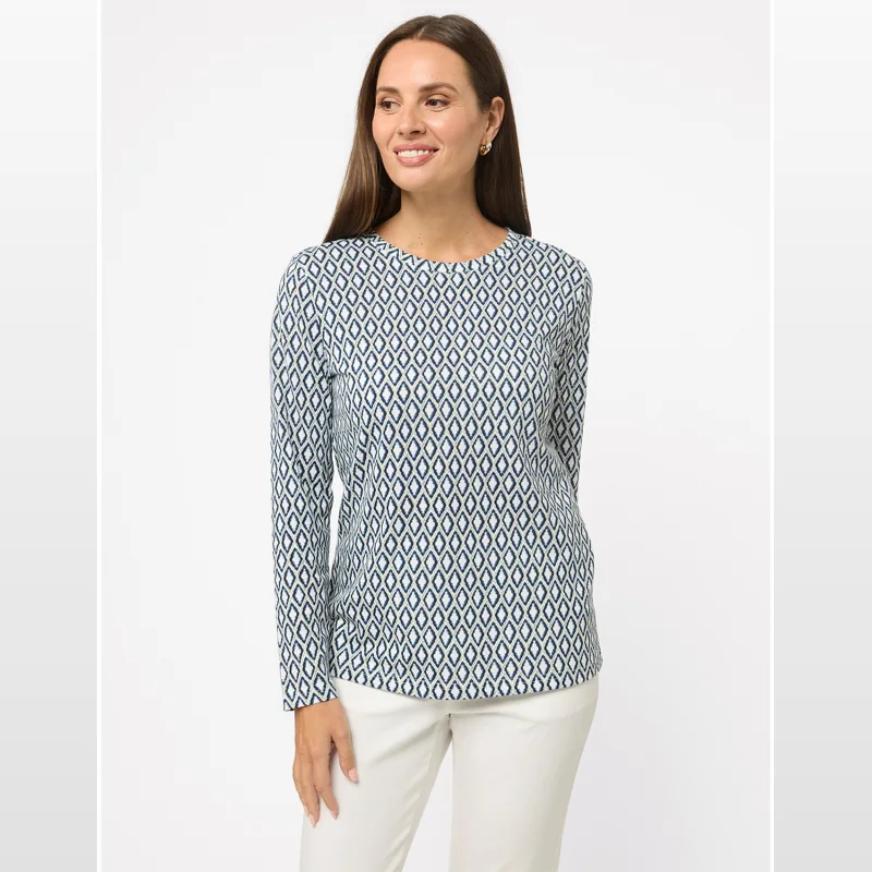 Woman wearing a long-sleeved top with a navy and white geometric diamond print, paired with cream trousers.