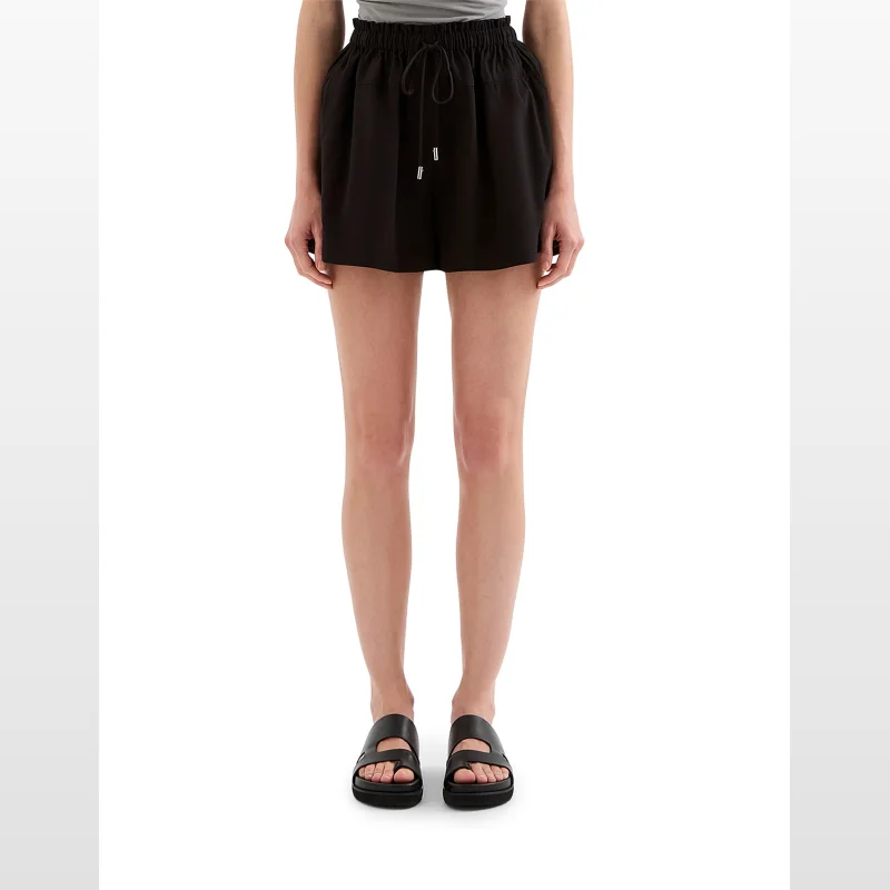 A woman wearing black NUDE LUCY Ila shorts with a paperbag waistband and drawcord.