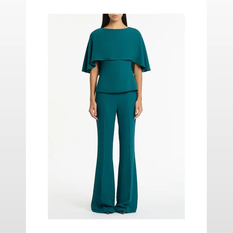 Woman wearing a teal Carla Zampatti Serpentine Crepe Cape Top with a fitted waist and a cape overlay, paired with matching flared trousers.