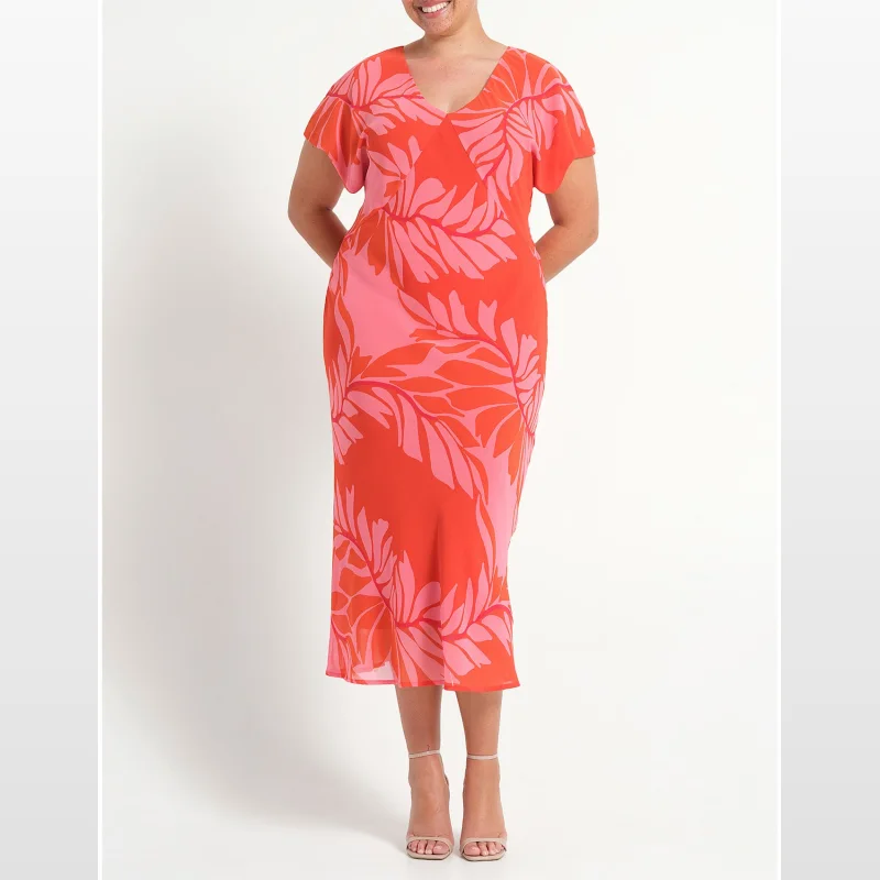 A woman wearing the Estelle Leyla Chiffon Midi Dress in Peony Rouge, a vibrant orange and pink floral print dress with short sleeves and a V-neckline.