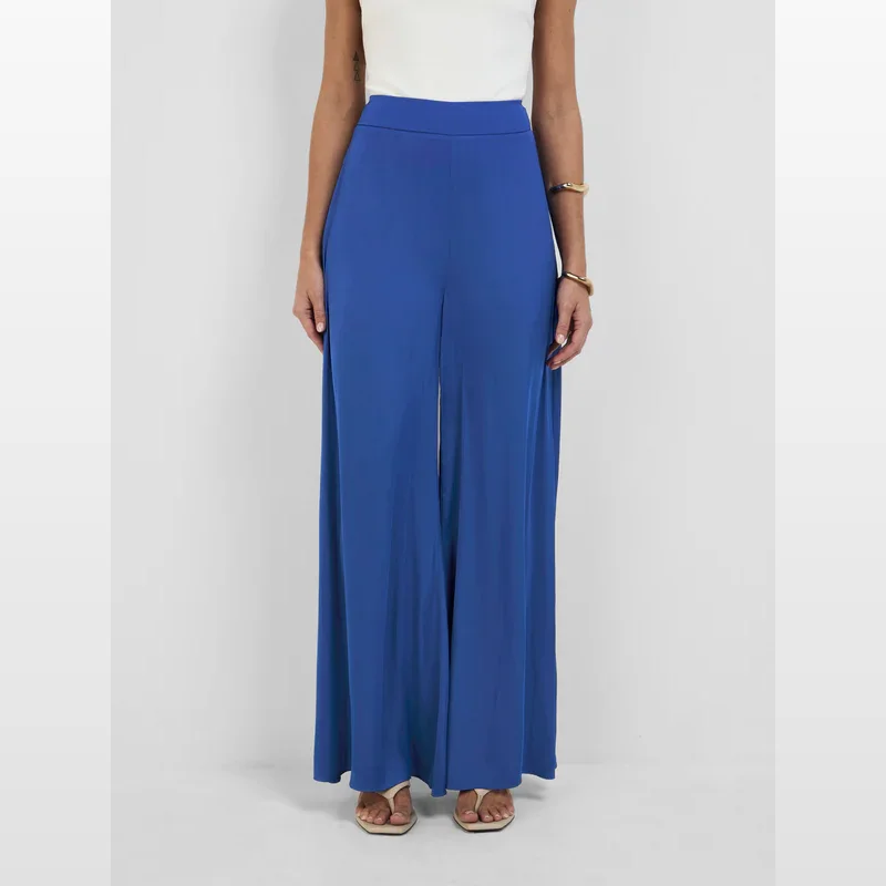 A woman wearing the blue Sheike Issy Pant, which are wide-leg trousers with a flattering fit and an elongated leg line.