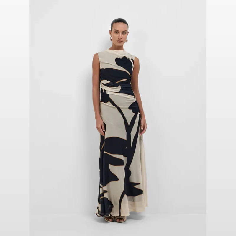 Woman wearing the Sheike Delilah Maxi Dress, a sleeveless, high-neck maxi dress with a bold black and beige abstract floral print and ruched detailing on the side.