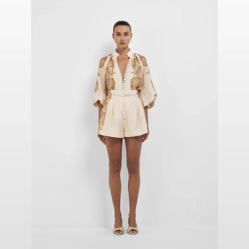 Woman wearing Sheike Mirage shorts and matching shirt, featuring a cream paisley print and tie belt.