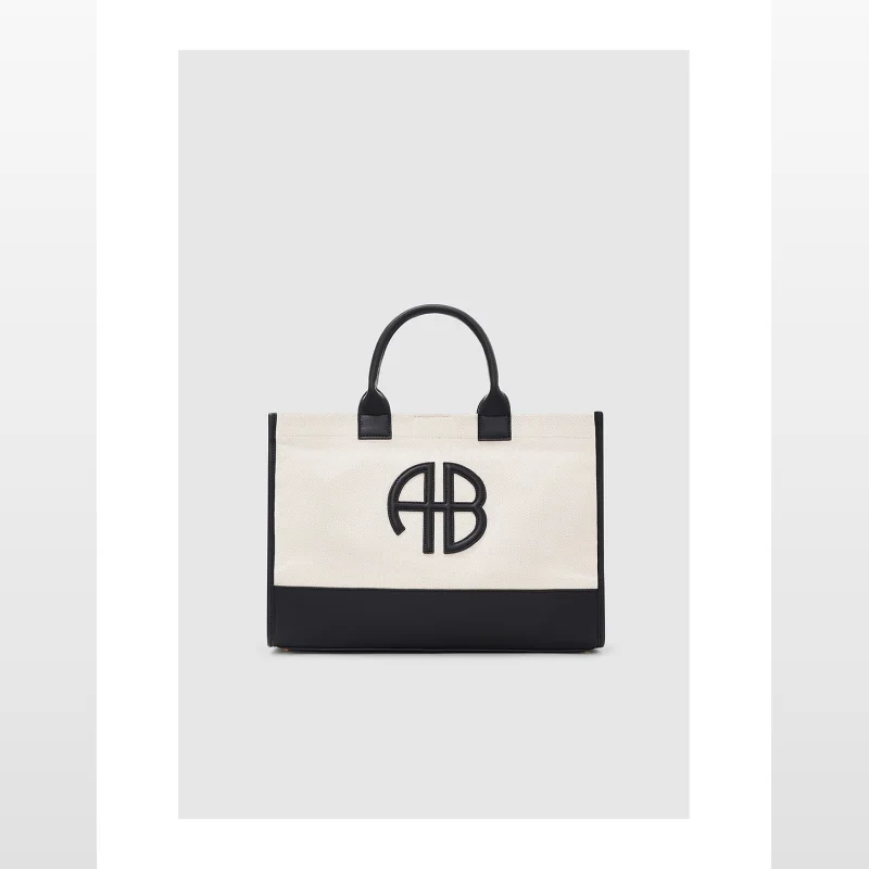 Anine Bing Medium Lara Tote Bag in natural cotton canvas with black leather accents and a prominent black 'AB' monogram.
