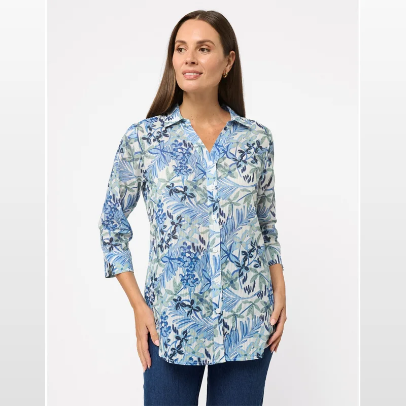 Woman wearing a blue and green floral print 3/4 sleeve collared shirt with a button-up front.