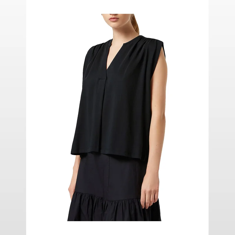 Woman wearing a black, short-sleeved, drapey V-neck t-shirt with gathered shoulders.