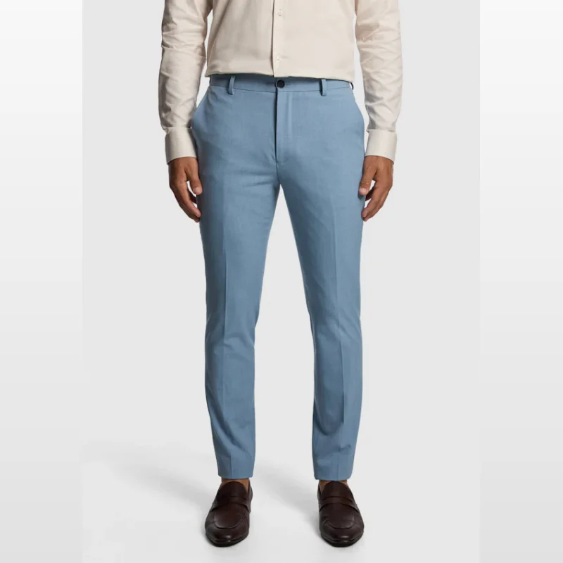 Man wearing light blue skinny fit dress pants with a beige shirt and brown loafers.