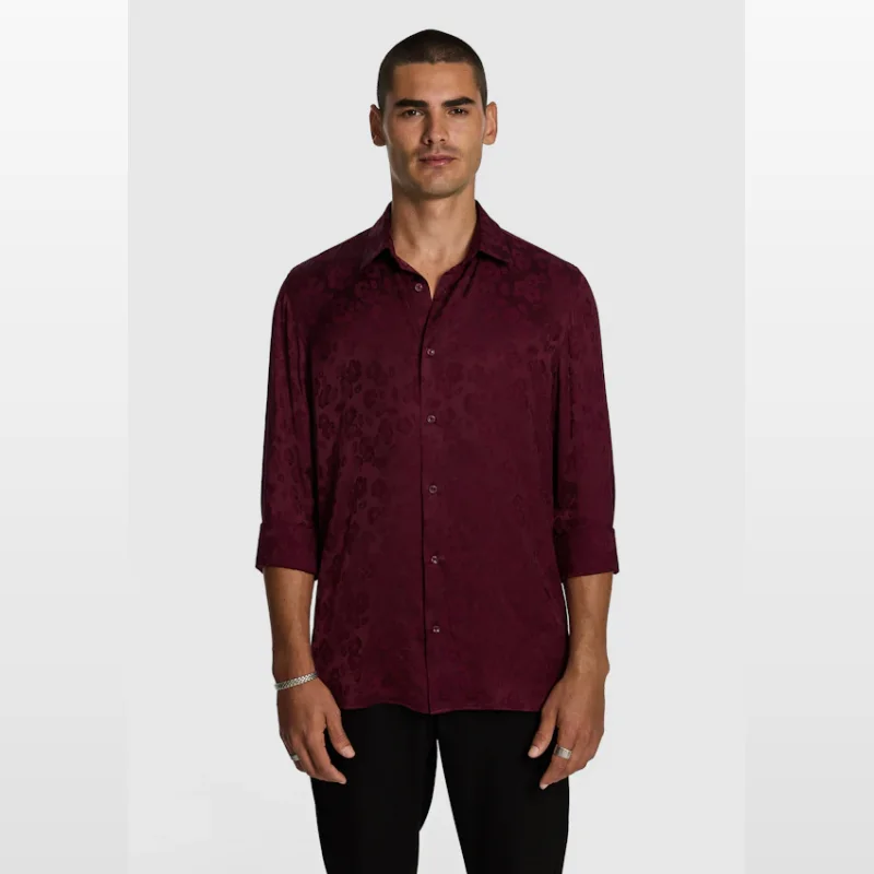 Man wearing a burgundy long-sleeved jacquard shirt with a floral pattern, cuffed sleeves, and a regular fit.