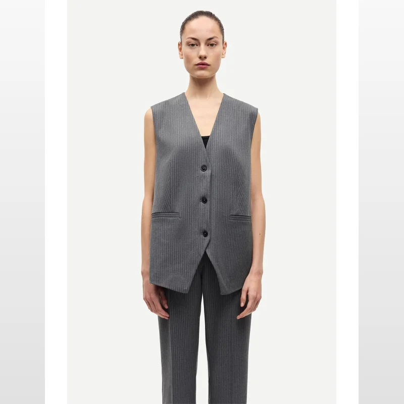 Woman wearing a grey pinstripe SAMSOE SAMSOE Saleni Vest with a V-neck and button closure.