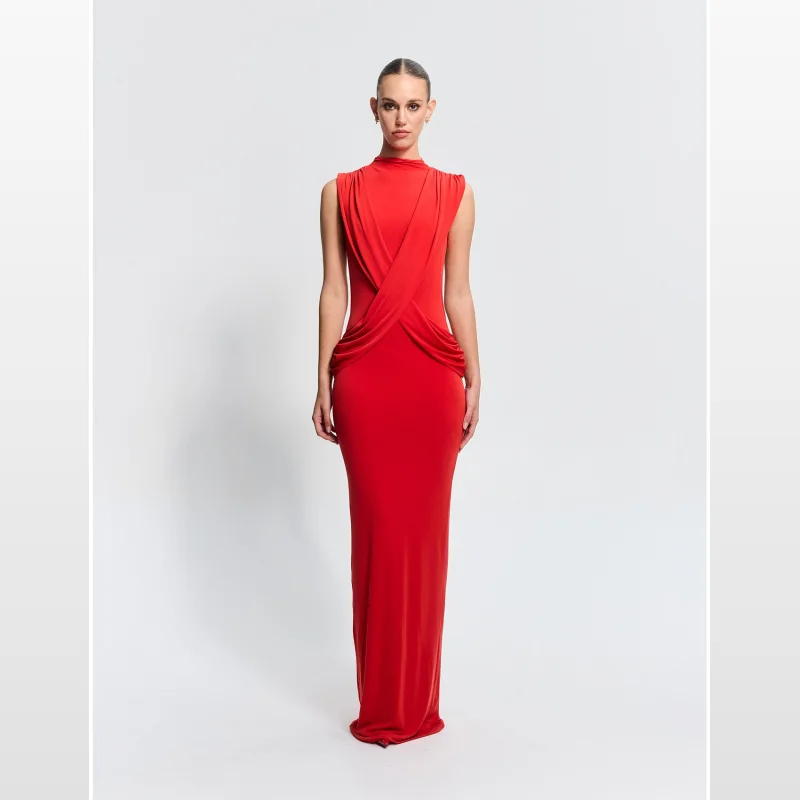 Woman wearing the Effie Kats Avalon Gown, a floor-length red dress with a high neckline, sleeveless design, and draped detailing across the bodice and back.