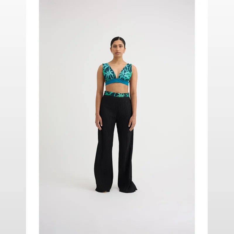 Woman wearing black wide-leg pleated pants with a tropical print bikini top.