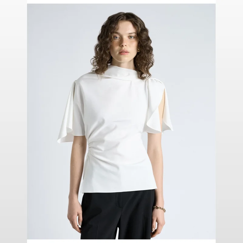 Woman wearing a white CUE crepe draped neck top with short sleeves and side-waist ruching.
