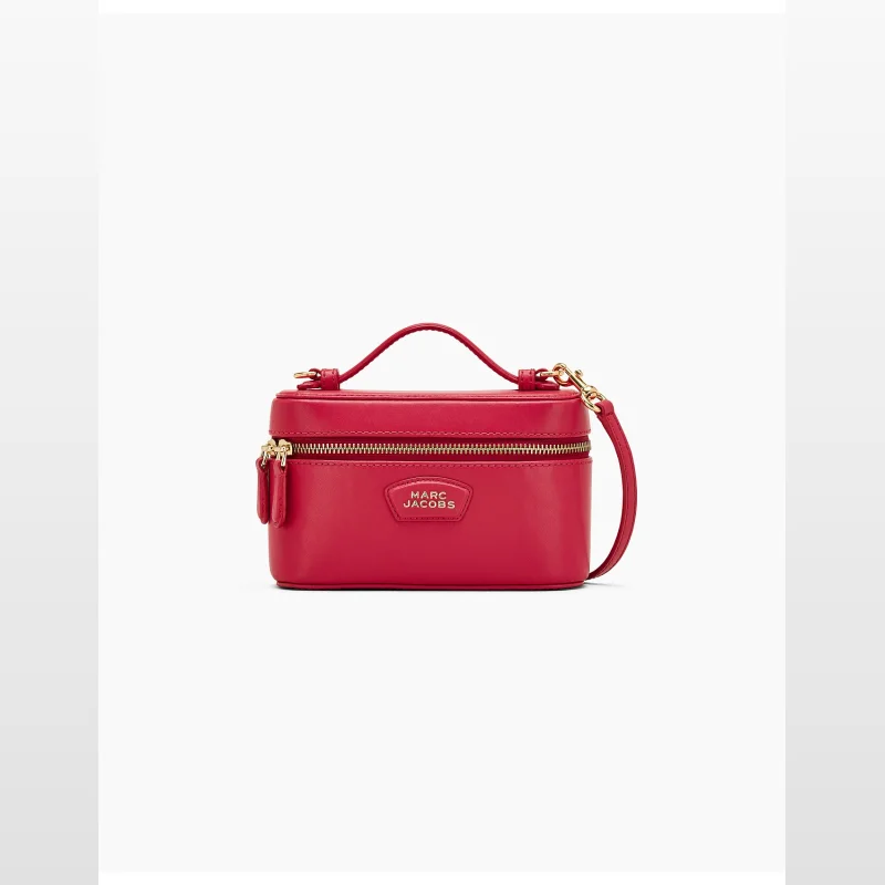 A red Marc Jacobs E/W Vanity bag made of smooth leather, featuring a top handle, zip-around closure, and a detachable crossbody strap.
