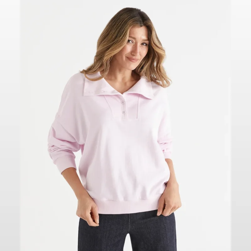 Woman wearing a light pink Sussan ribbed jumper with a collared neckline and button closures.