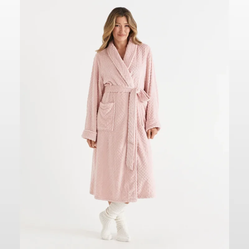 Woman wearing a pale pink, knee-length jacquard robe with a belt and pockets, standing against a white background.