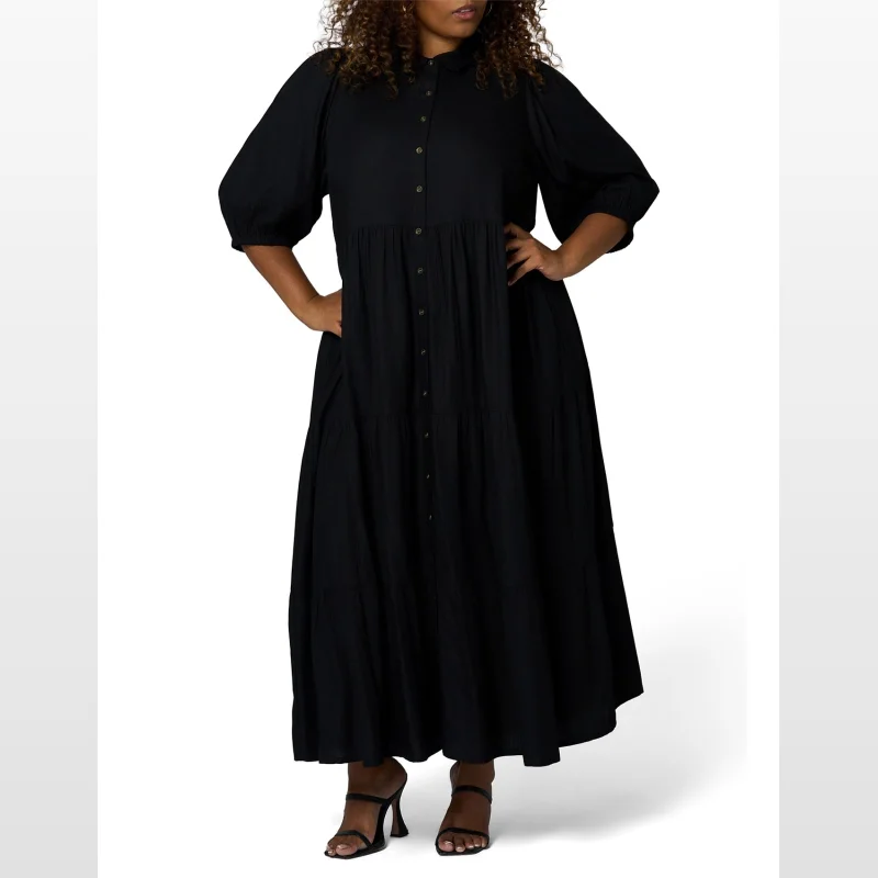 A plus-size model wears a black midi shirt dress with a tiered skirt and 3/4 sleeves.