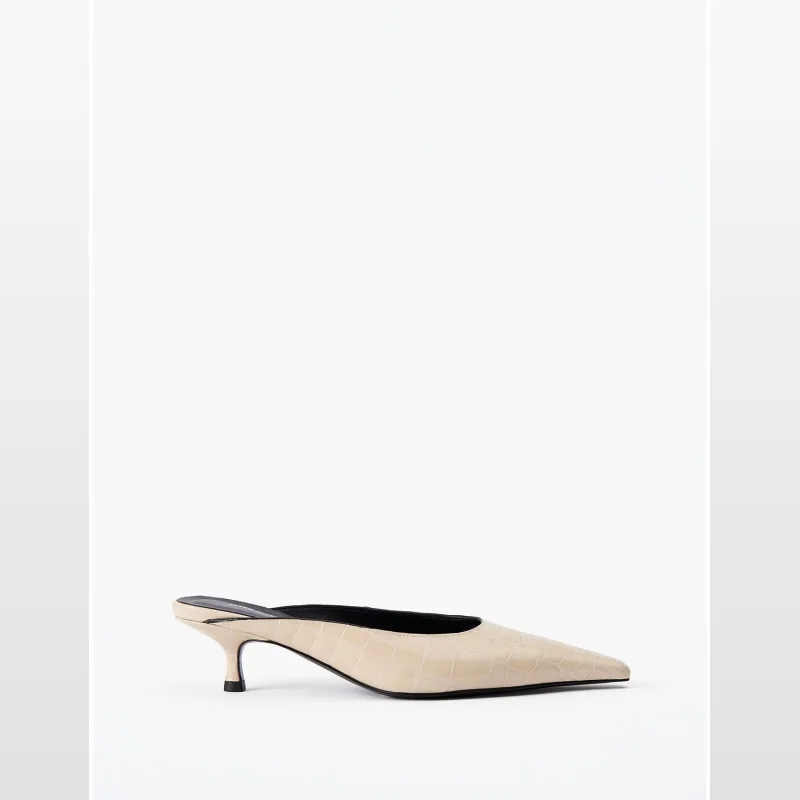 A single Alias Mae Geneva mule in a beige crocodile-embossed leather with a pointed toe and a low kitten heel, presented on a white background.