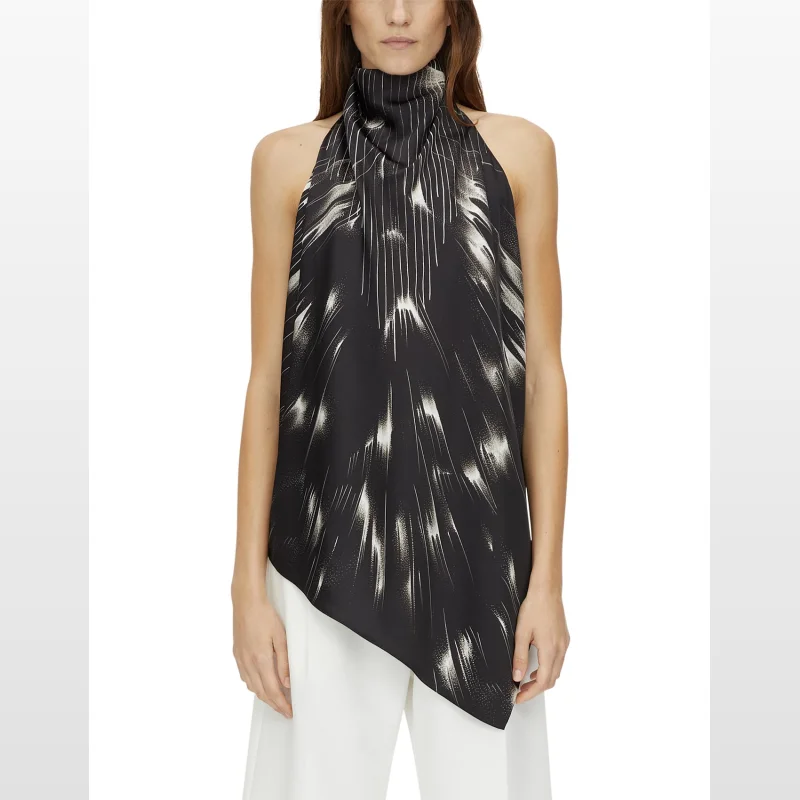 Woman wearing a black and white printed Camilla and Marc Arvid Halter Neck Top with a high neckline and open back, paired with white trousers.