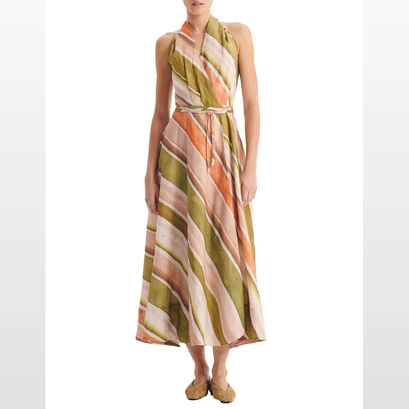 Woman wearing a striped, halter neck linen maxi dress with a tie waist and a full swing skirt.