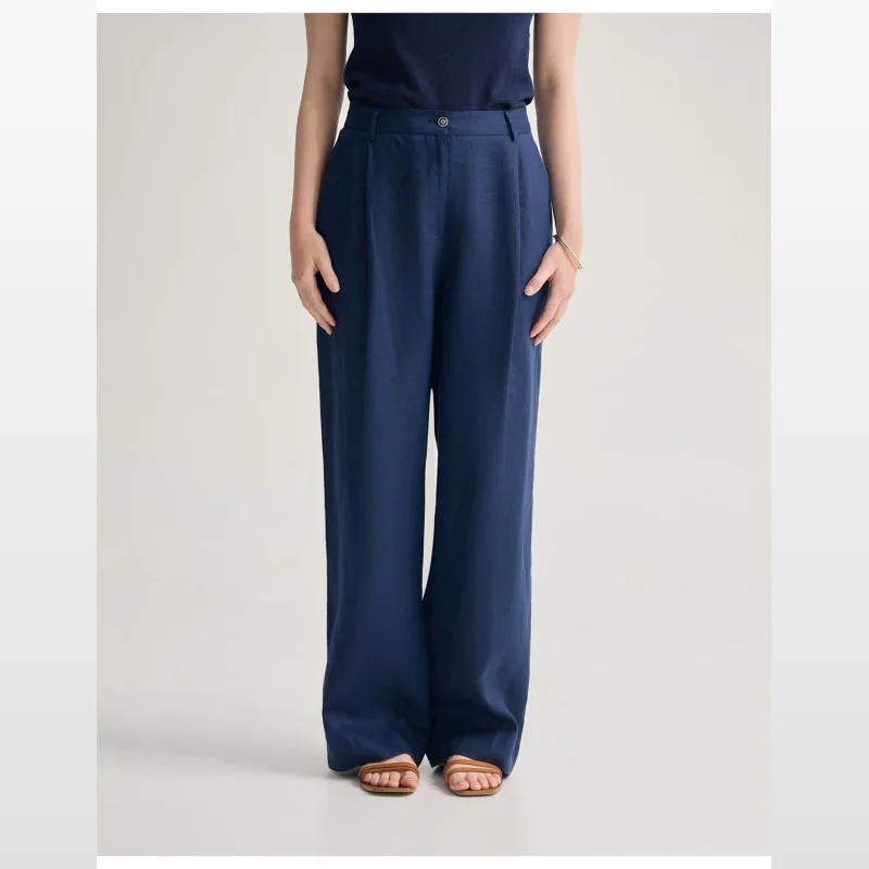 Woman wearing navy blue Oxford Lola Linen Pants with an elastic waistband and relaxed fit, paired with a navy top and tan sandals.