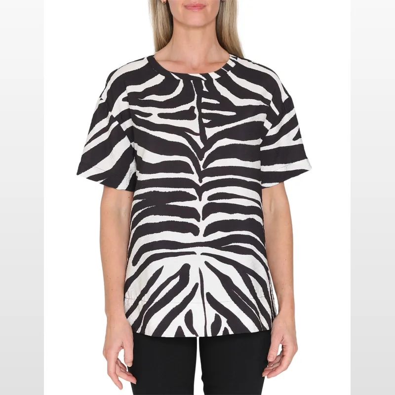 Woman wearing a black and white zebra print short sleeve blouse with a round neckline.
