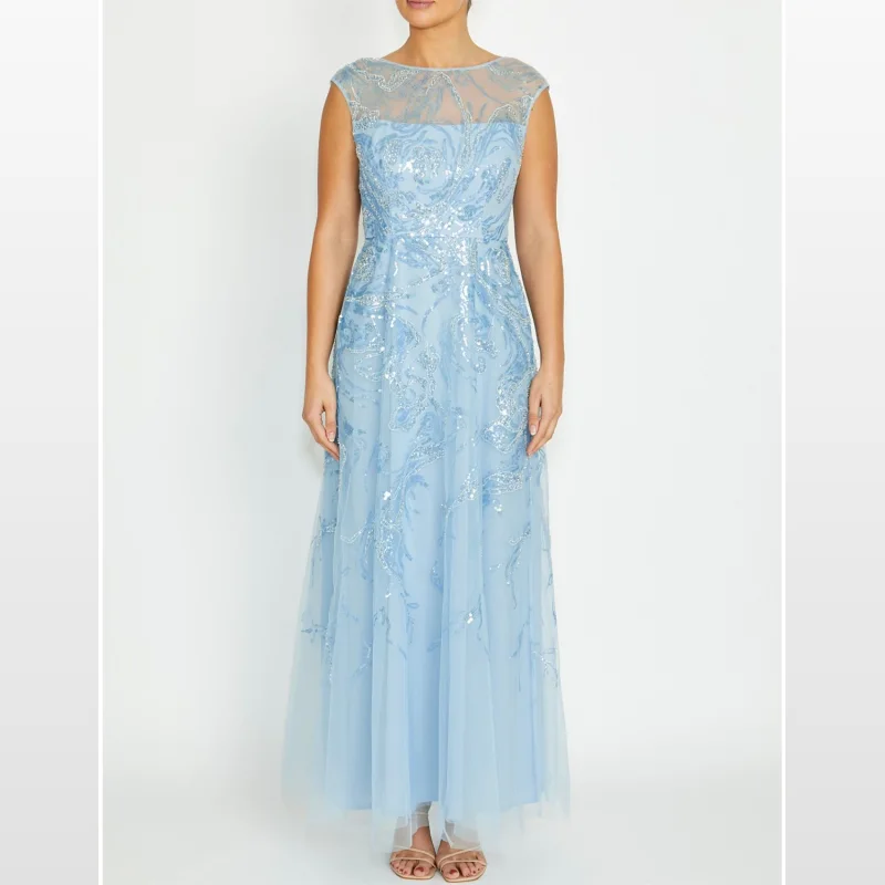 A woman wearing the Anthea Crawford Catalina Sky Blue Sequin Gown, a full-length A-line dress with a round neckline, sheer yoke, and extended shoulders, adorned with sky blue sequins and embroidery.